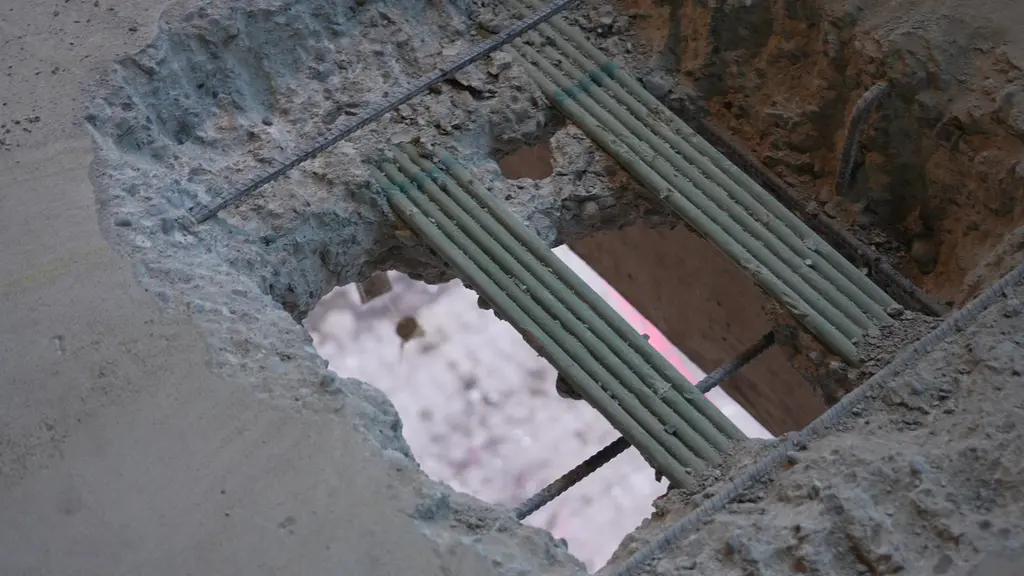 Close-up view of exposed green rebar and concrete from a slab cutout, showing structural reinforcement detail.