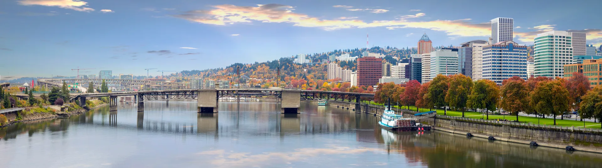 Scenic view of downtown Portland, Oregon, with bridges, waterfront, and fall-colored trees along the Willamette River.