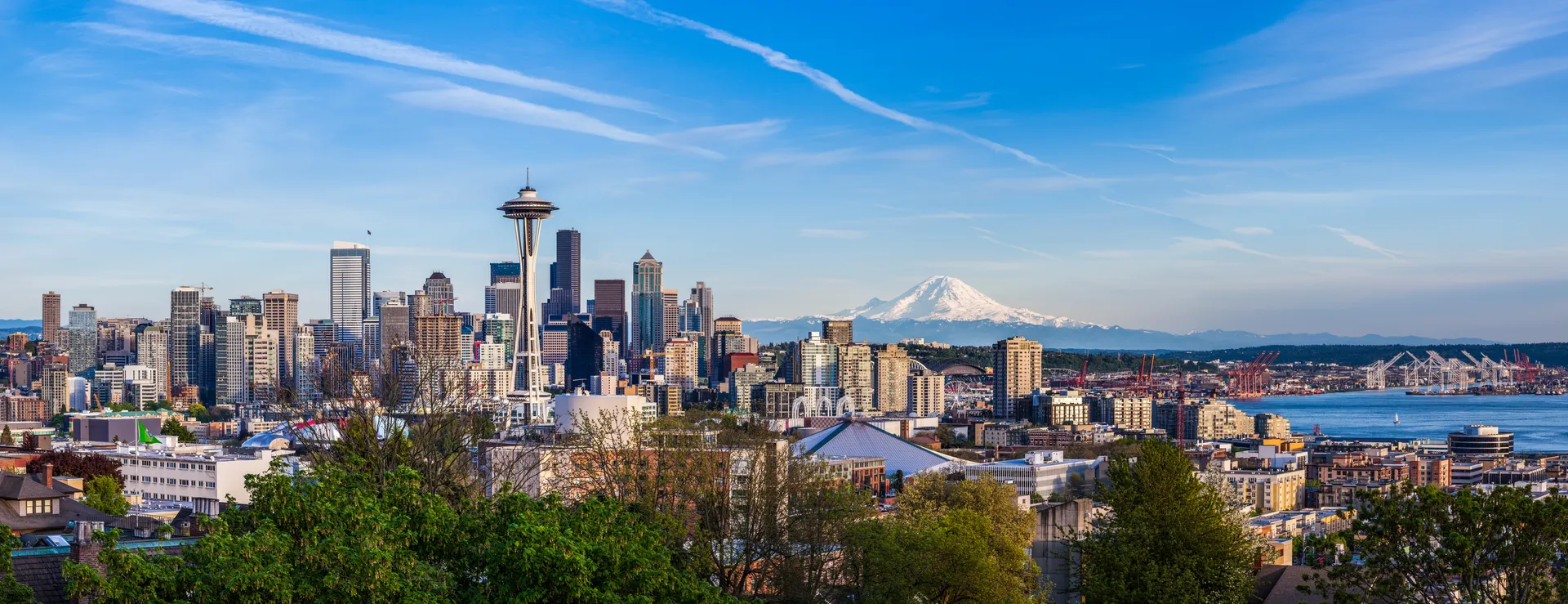 View of downtown Seattle with the Space Needle, Mount Rainier in the background, and Elliott Bay on a clear day.