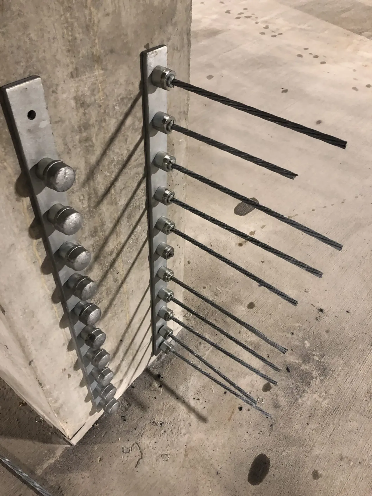 Close-up of post-tensioned cable anchors secured to a concrete column as part of a structural retrofit system.