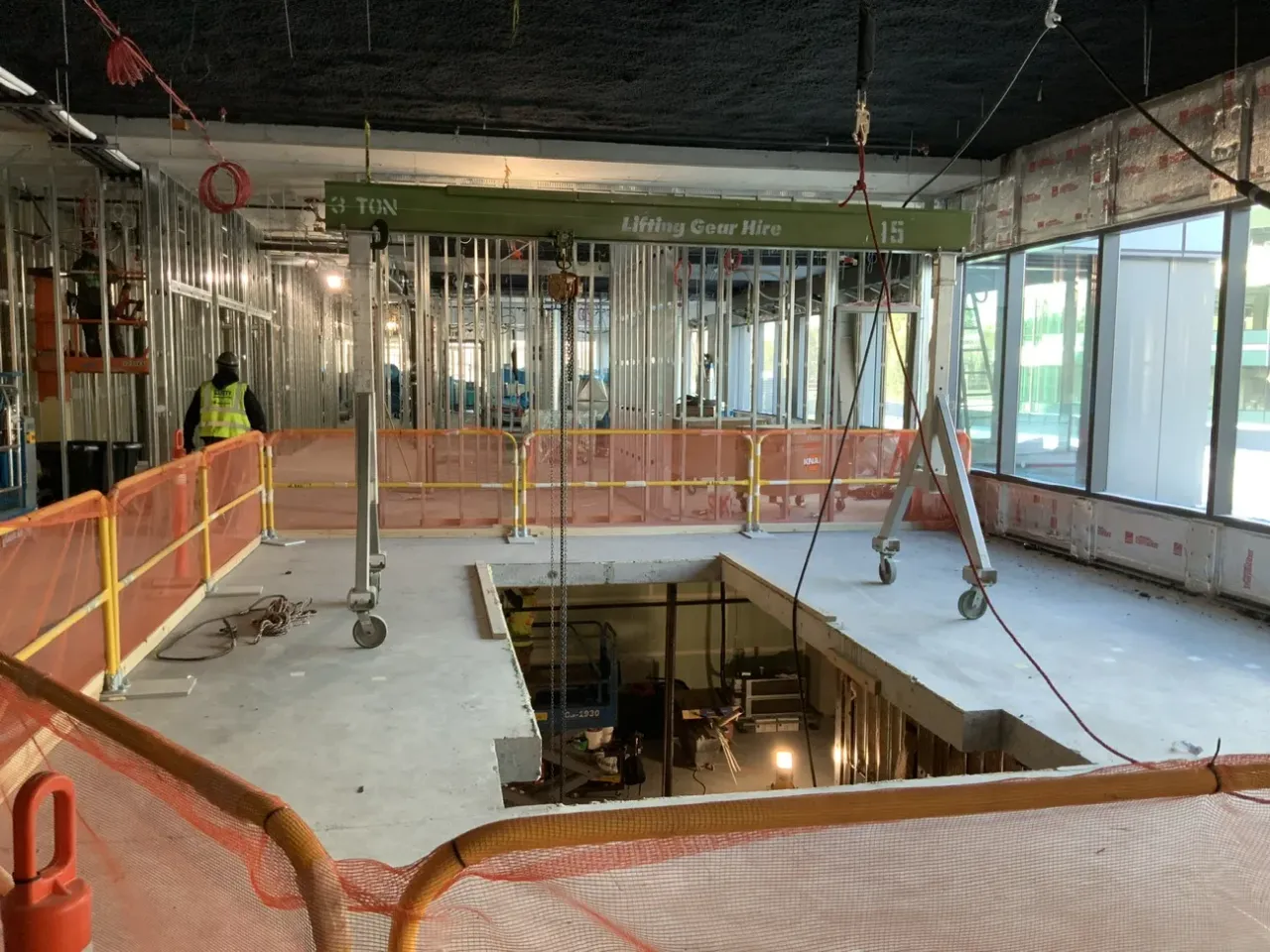 Large circular slab opening under construction across two floors with fall protection barriers at Kirkland Urban site.