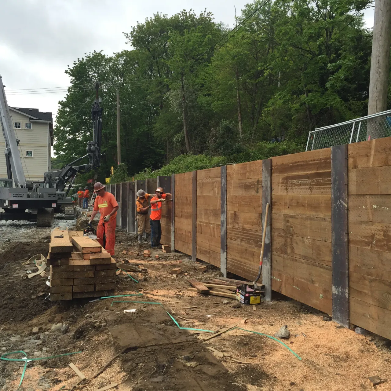 Construction crew installs timber lagging between steel soldier piles to form a shoring wall at MLK Townhomes site.