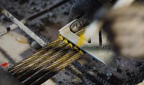 Worker measures exposed steel tendons during a post-tension slab retrofit without the use of shoring.