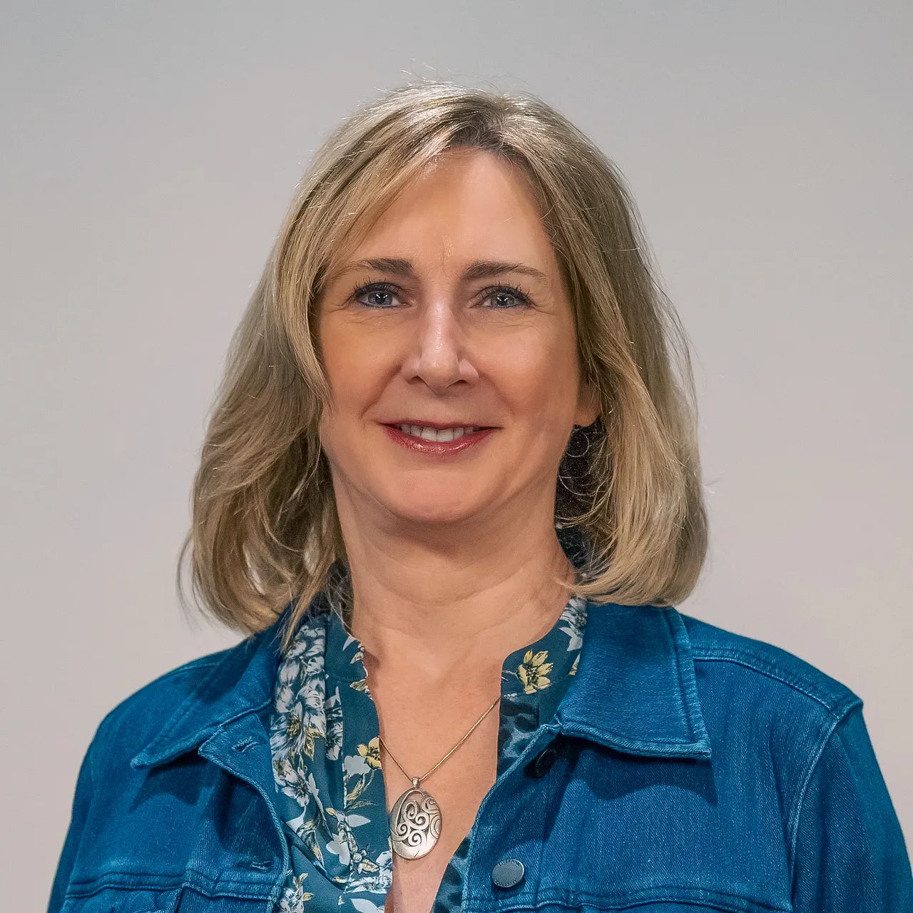 Cynthia Thompson smiling in a denim jacket and floral blouse, representing leadership at the company.