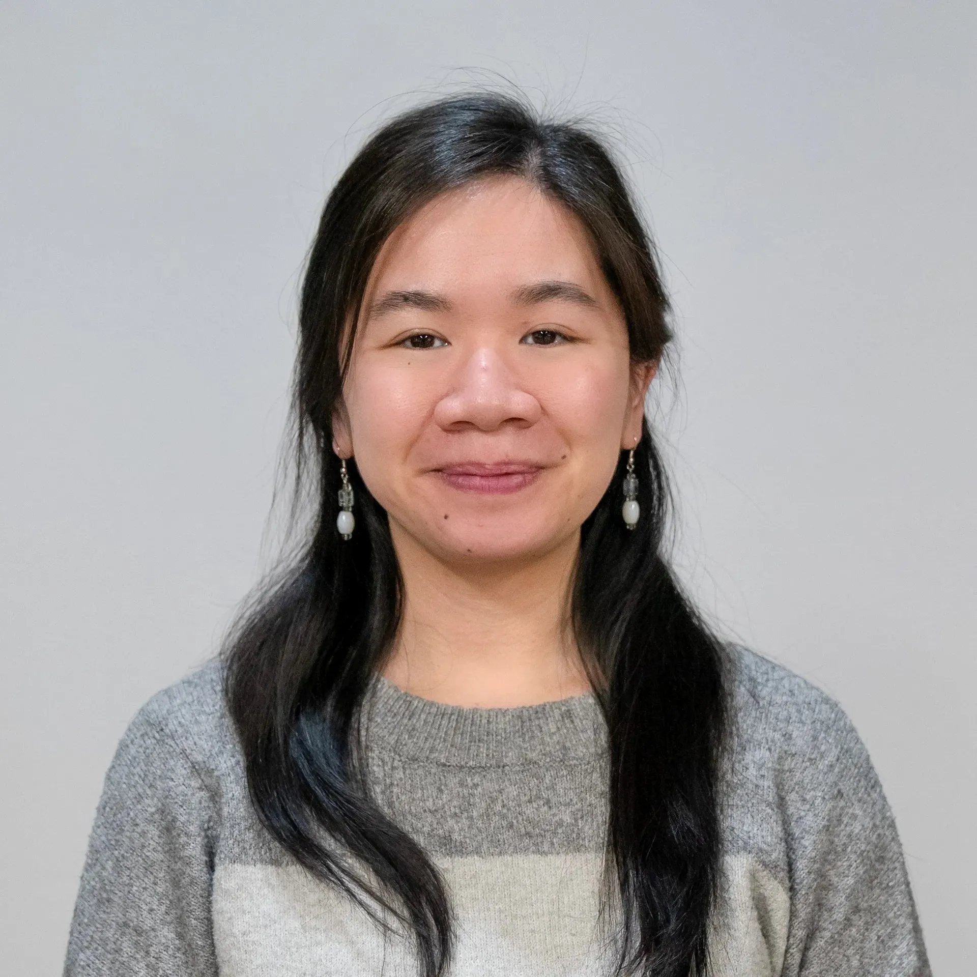 Rebecca Vu in a grey sweater, smiling warmly as part of the company’s office administration team.