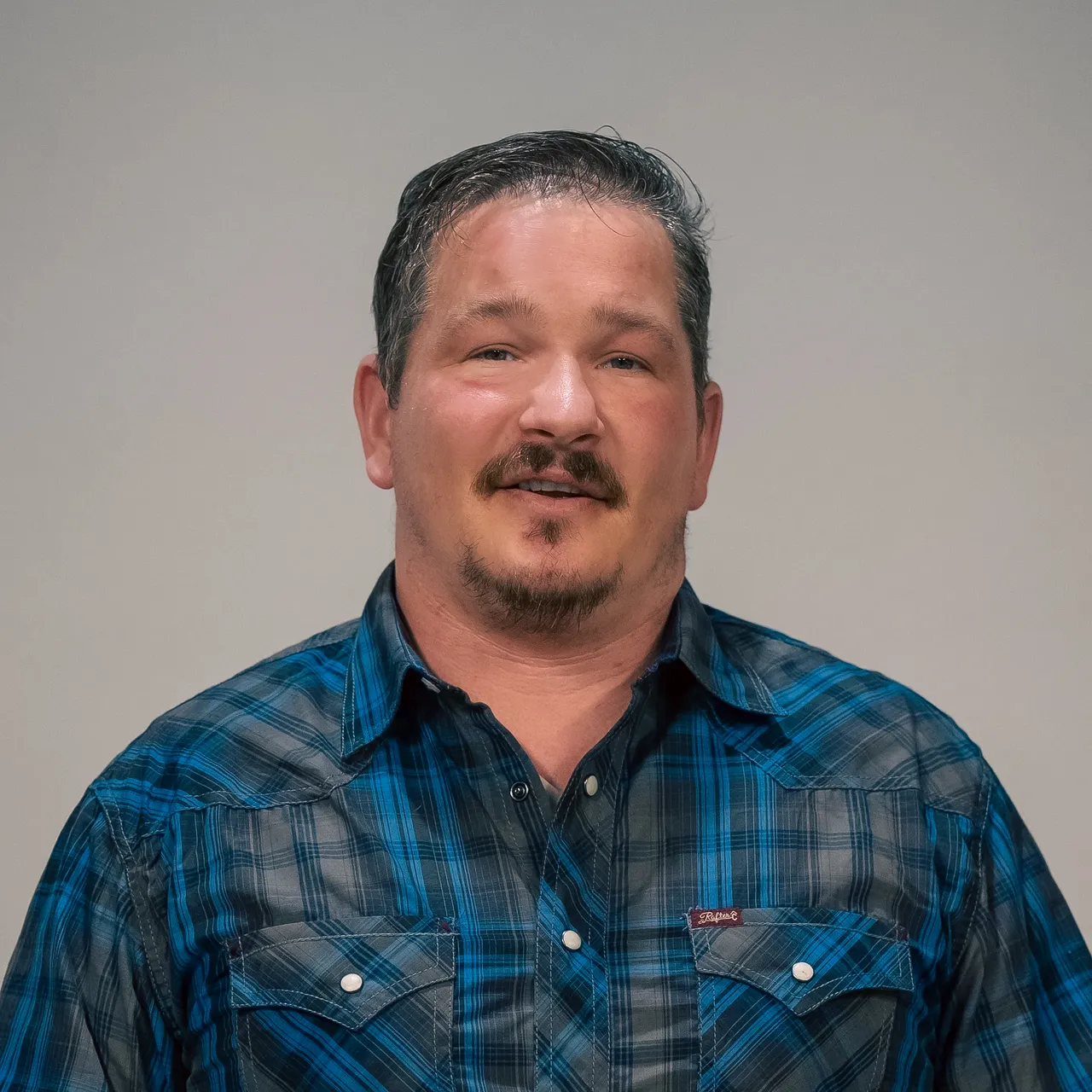 Shaun Thompson in a blue plaid shirt, representing field operations and on-site project leadership.