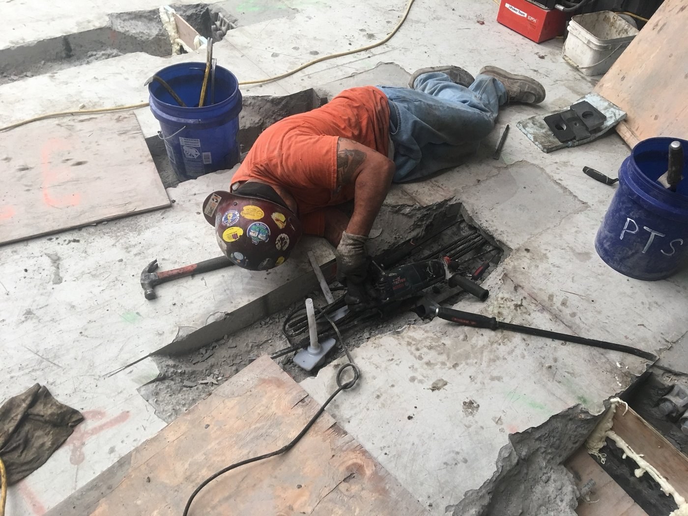 Rick Thompson working an anchor pocket on Building 122, face-down in a freshly chipped opening.