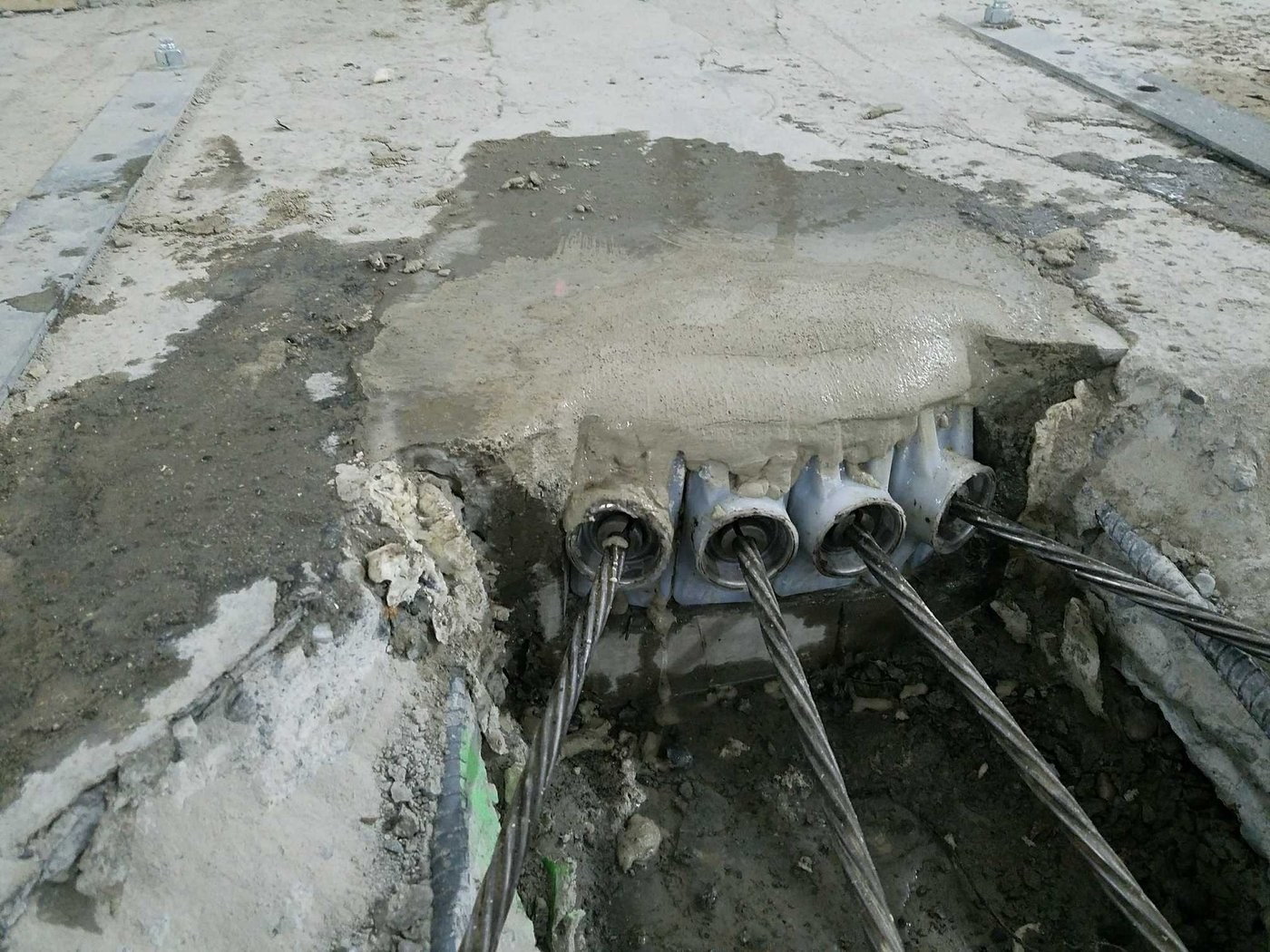 An original anchor assembly exposed after controlled concrete removal. Getting the wedges out of hardware this old took a tool the PTS team built for this job.